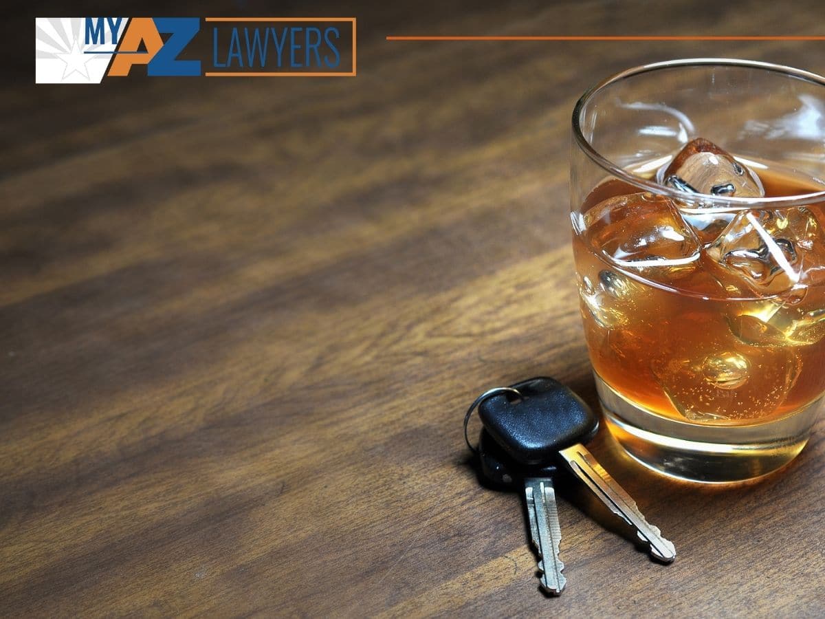 Glass of whiskey and car keys on wooden table