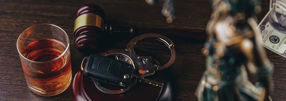 Glass of whiskey next to car keys and gavel