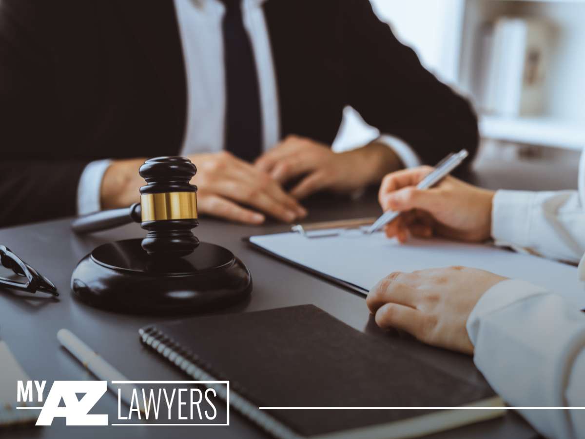 Lawyers discussing criminal charges at a desk, with a gavel and documents in view