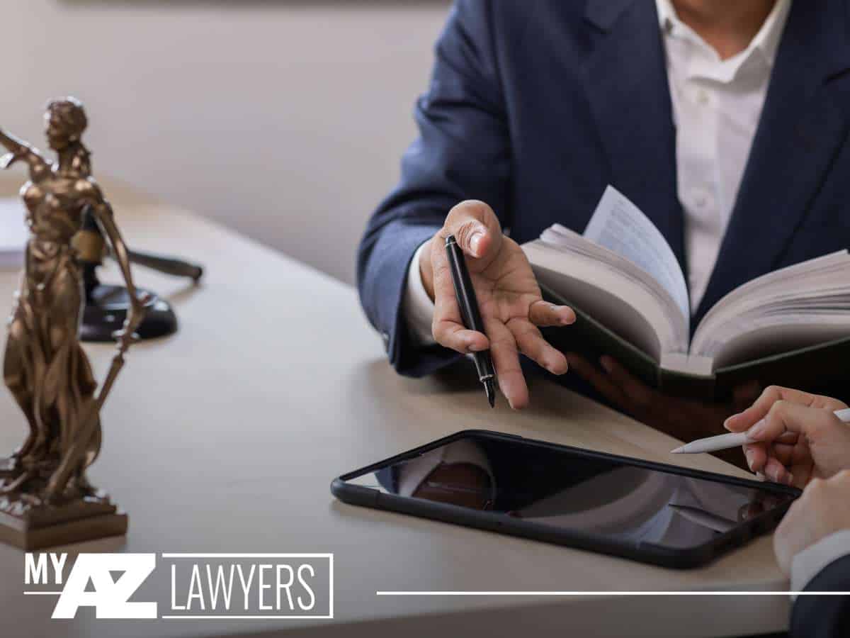 A lawyer discussing child custody matters with a client, holding a pen and legal book at a desk with a tablet and Lady Justice statue